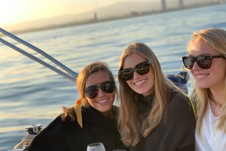 a woman wearing sunglasses standing next to a body of water
