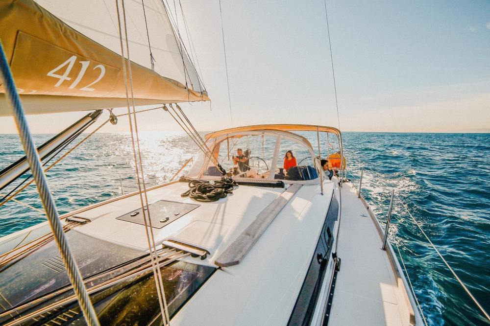 Sailboat with people on deck, ocean view under a clear sky.