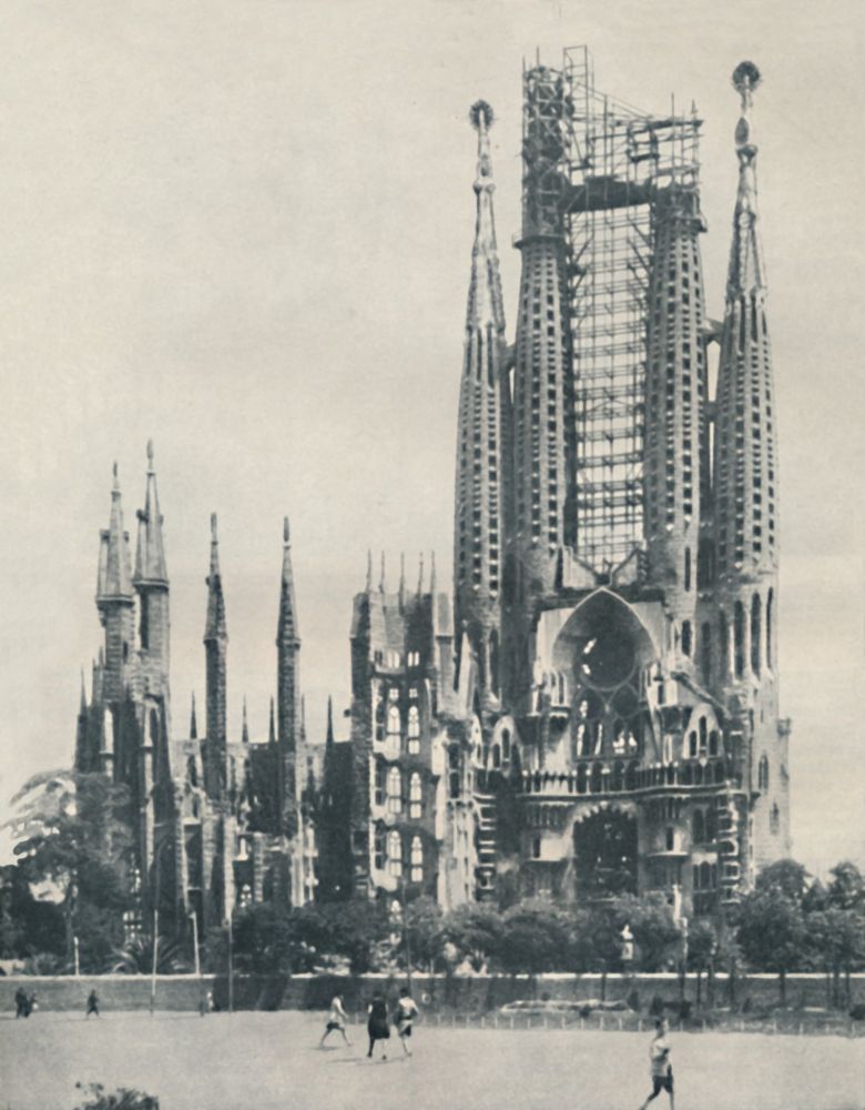 Historic photo of Sagrada Familia under construction, with visible scaffolding and cranes.