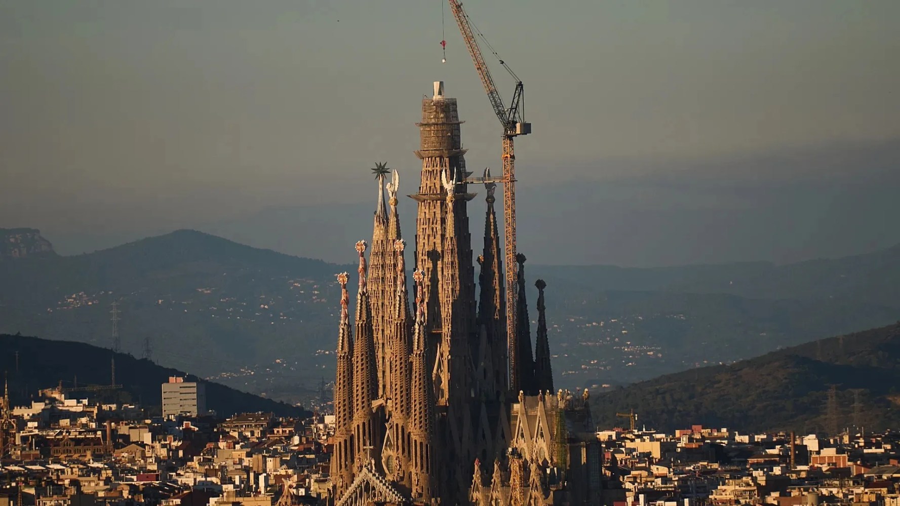 Large Gothic cathedral with spires and construction crane in a cityscape.